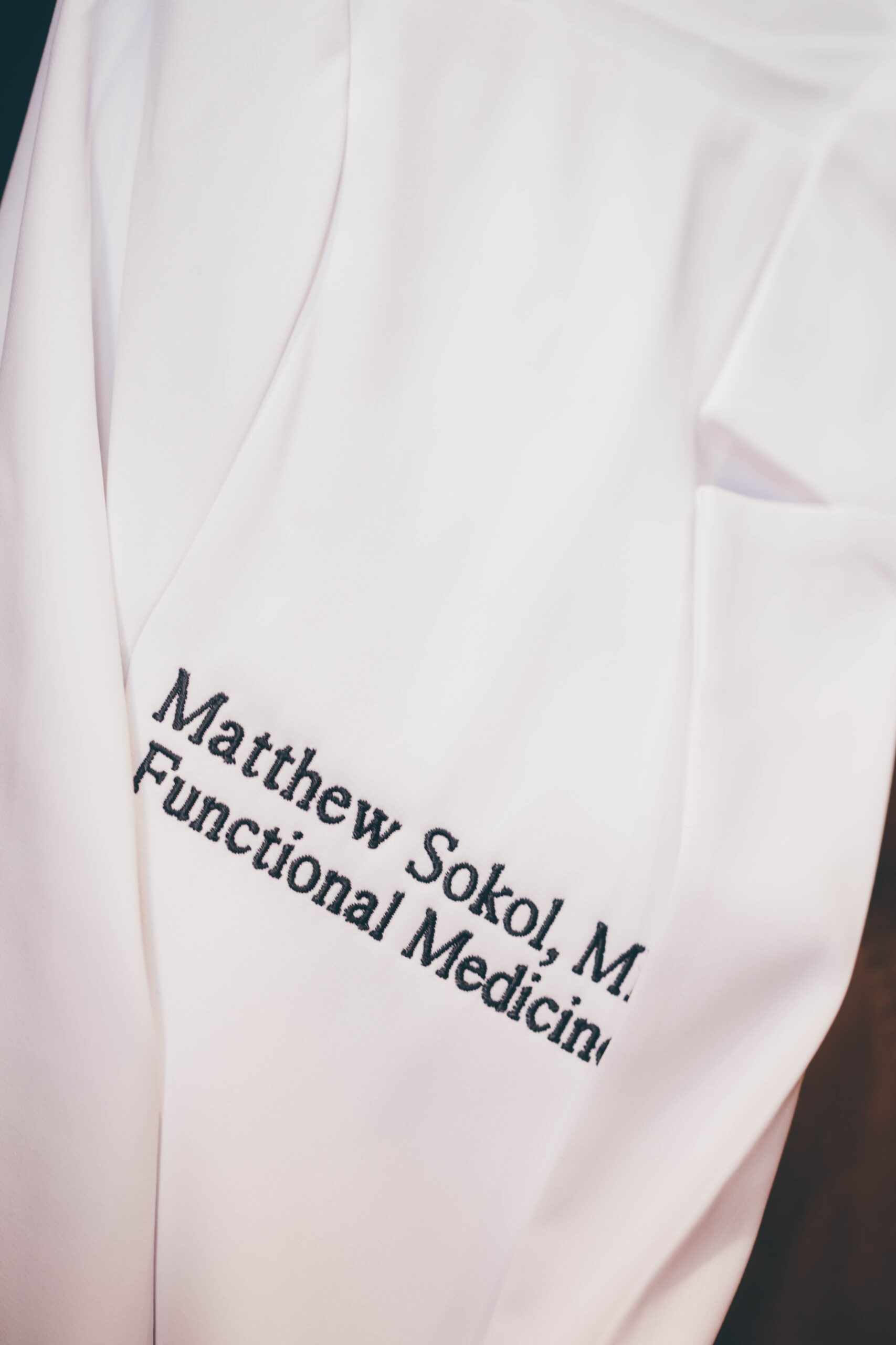 Close-up of a white lab coat embroidered with "Matthew Sokol, MD, Functional Medicine."