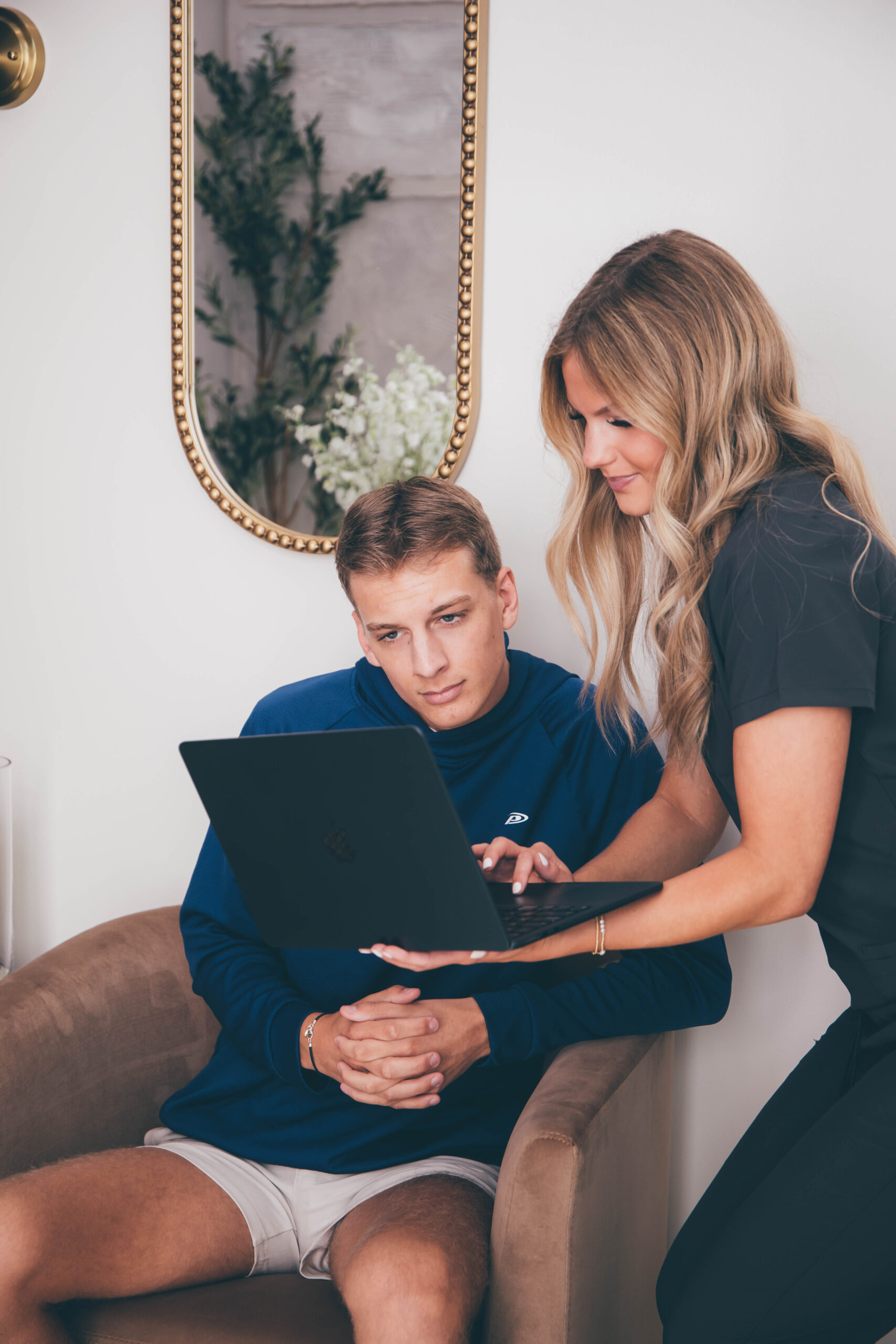 An Ivalo MD practitioner and a patient reviewing health data together on a laptop in a comfortable clinic setting during an integrative medicine Dallas consultation.