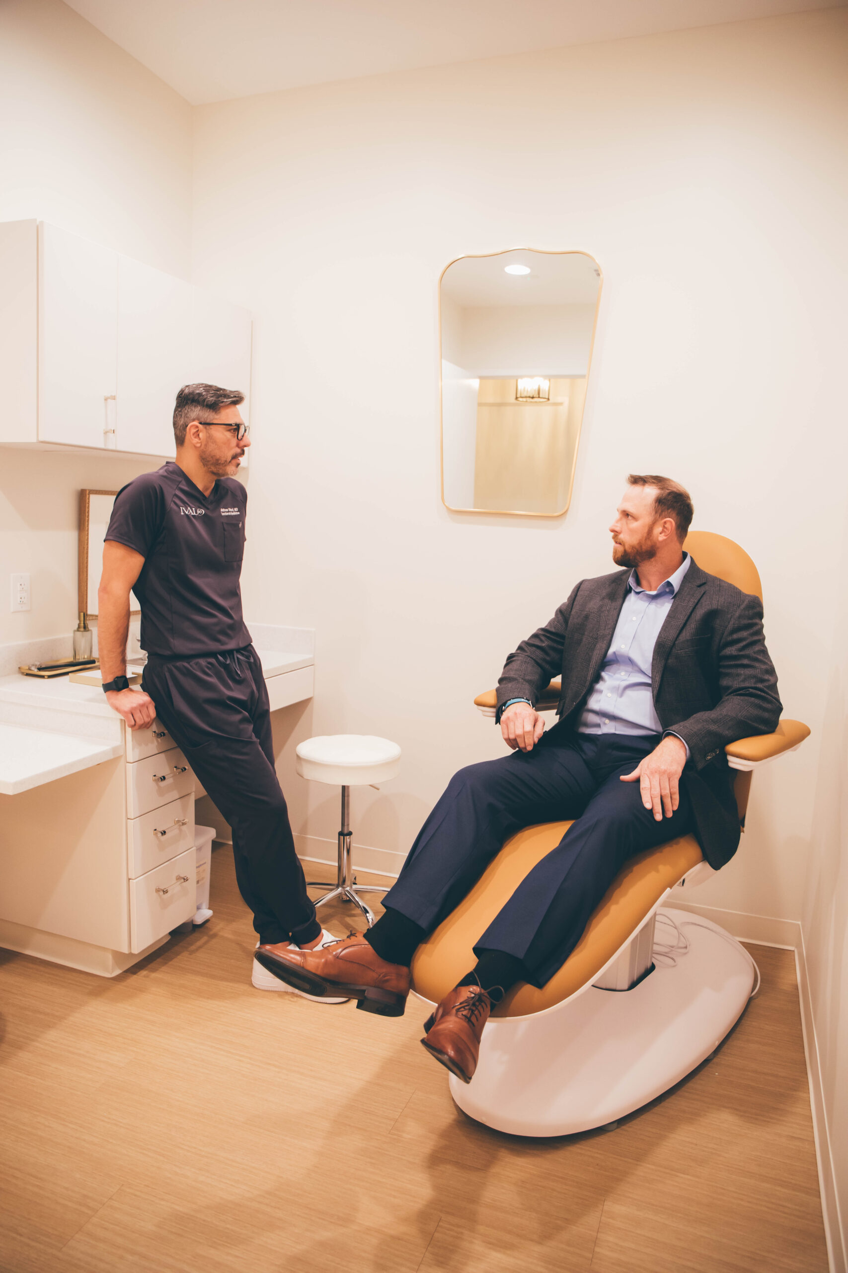 Dr. Sokol in scrubs talking to a patient seated in a clinical office in McKinney