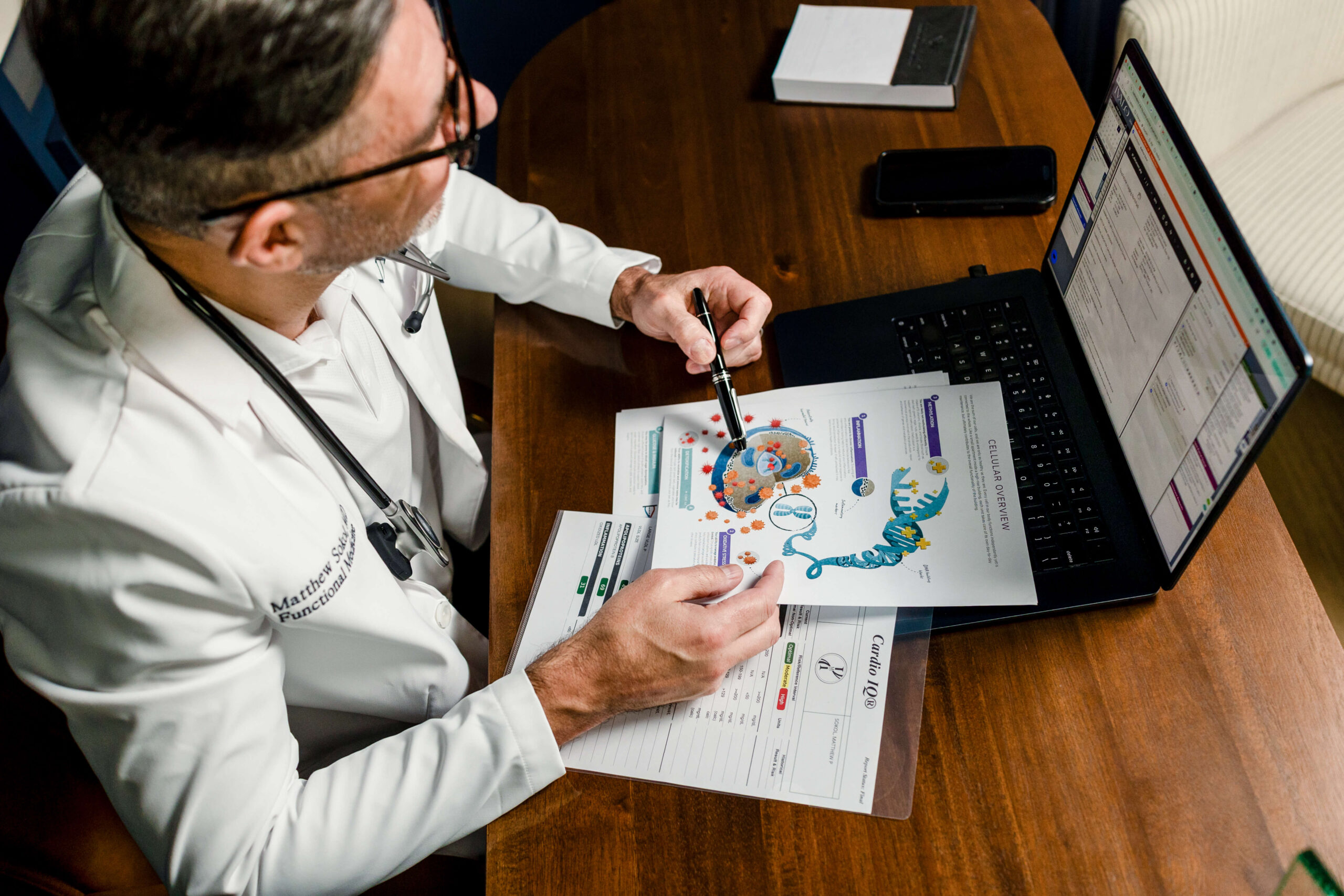 Dr. Sokol comparing printed lab charts with patient data on his laptop