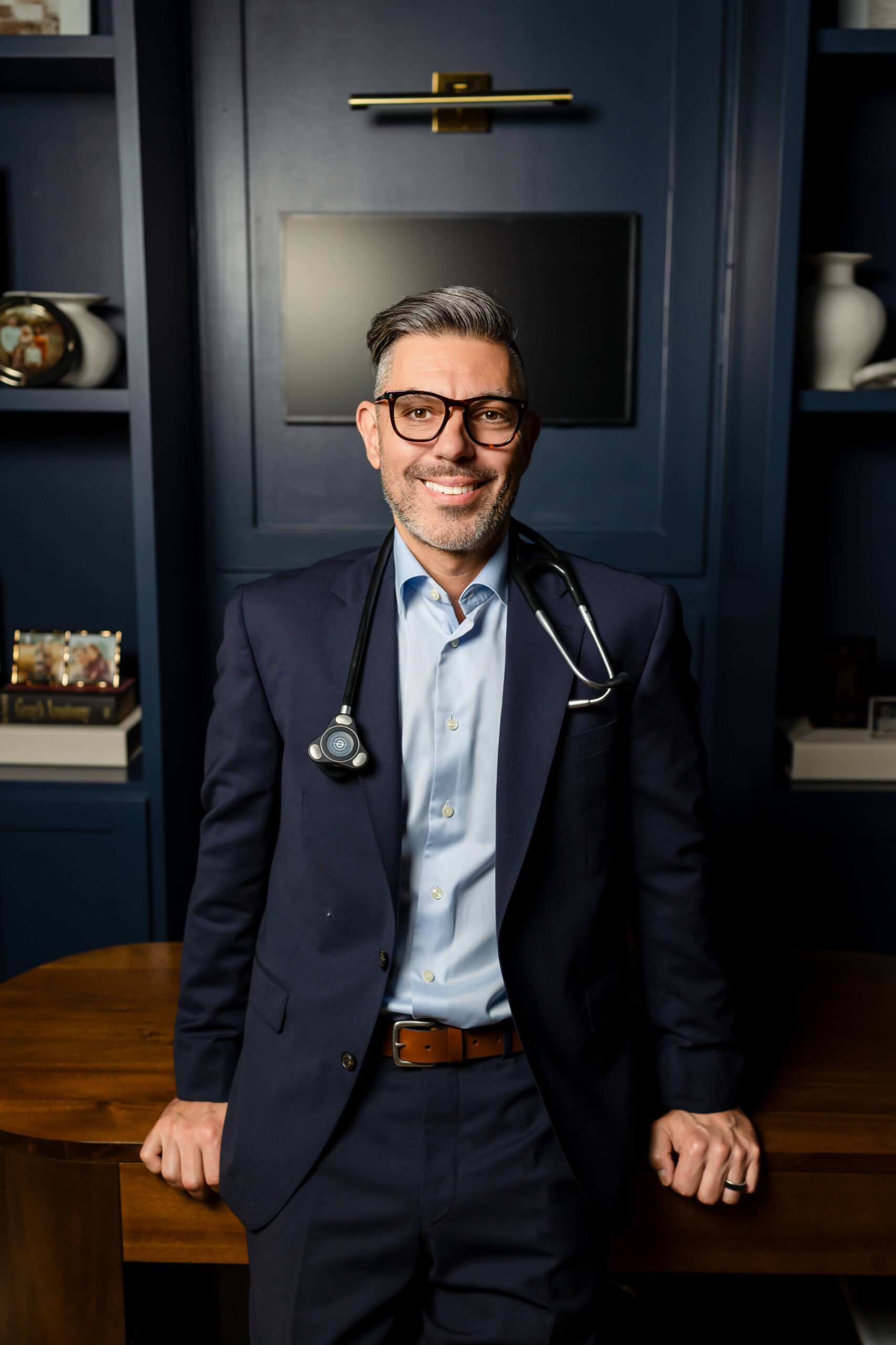 Dr. Sokol in a navy suit leaning against his desk at Ivalo MD in McKinney, TX